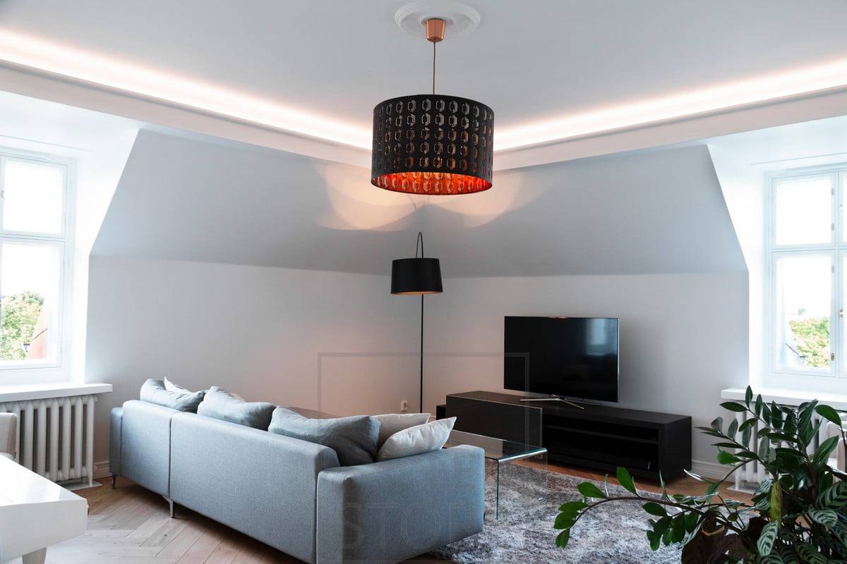 Dans le salon, le plafond est bordé d'une bande de plafond avec un éclairage indirect dirigé vers le plafond. L'éclairage est atmosphérique et doux, sans éblouissement.